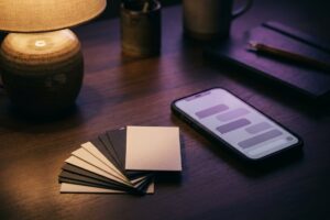 A dark desk lit by one lamp: a phone showing abstract chat bubbles beside a fan of cards, most face down.